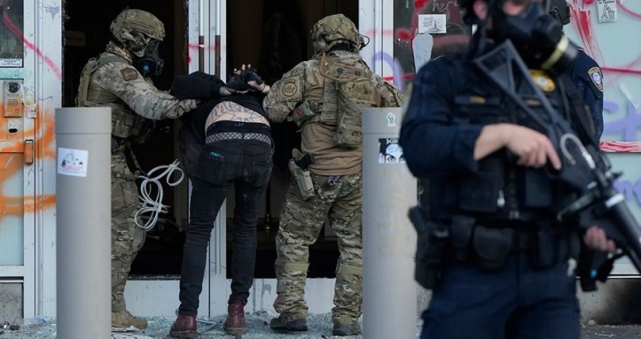 A person is arrested in Portland by heavily armed ICE officers dressed in army fatigues.